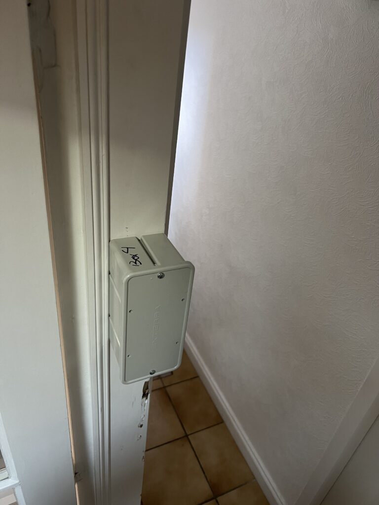 Station de piège-appât anti-termites fixée au mur d’une maison